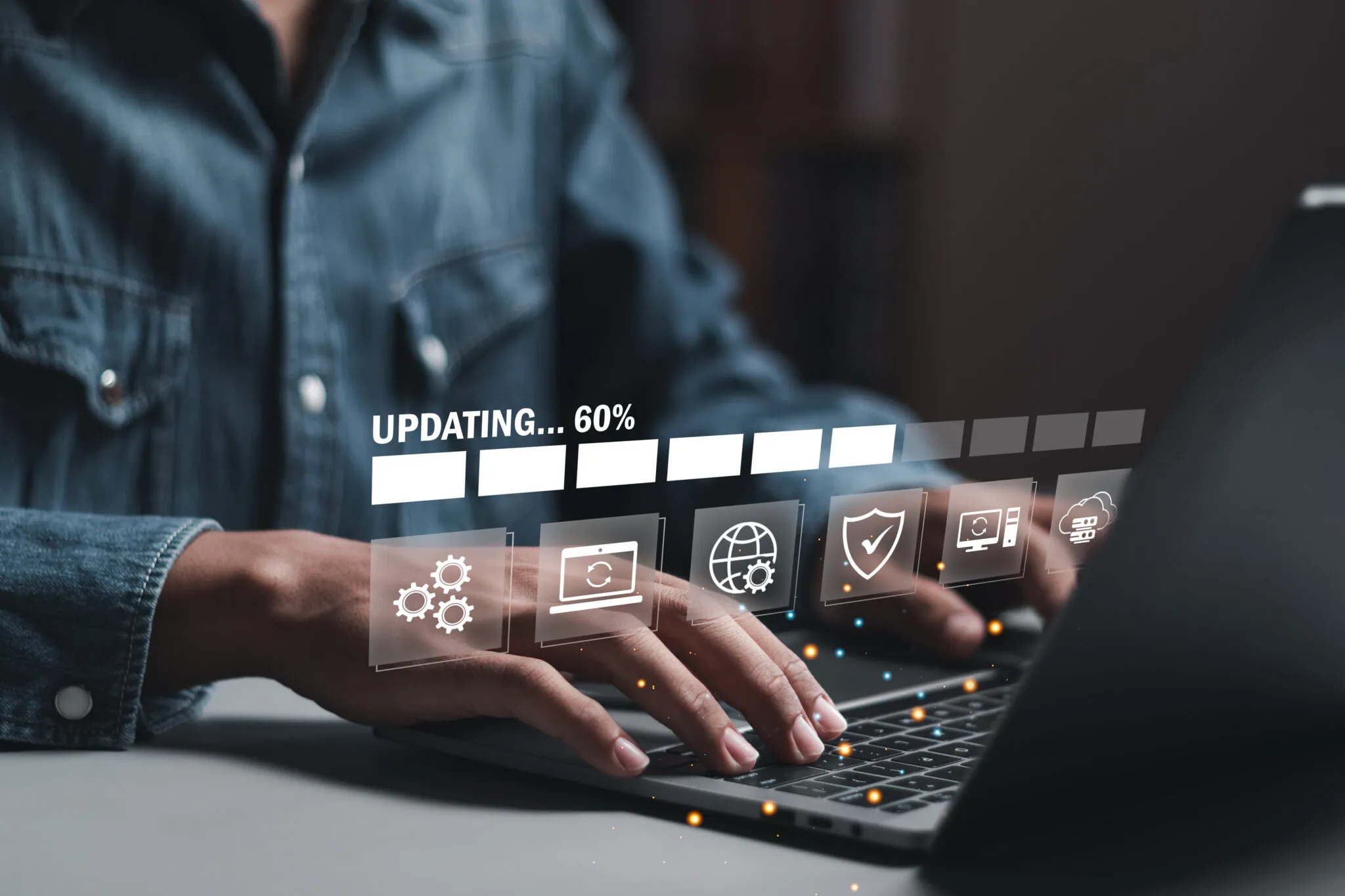 Hands typing on a laptop with a digital illustration showing computer icons and an updating load bar.