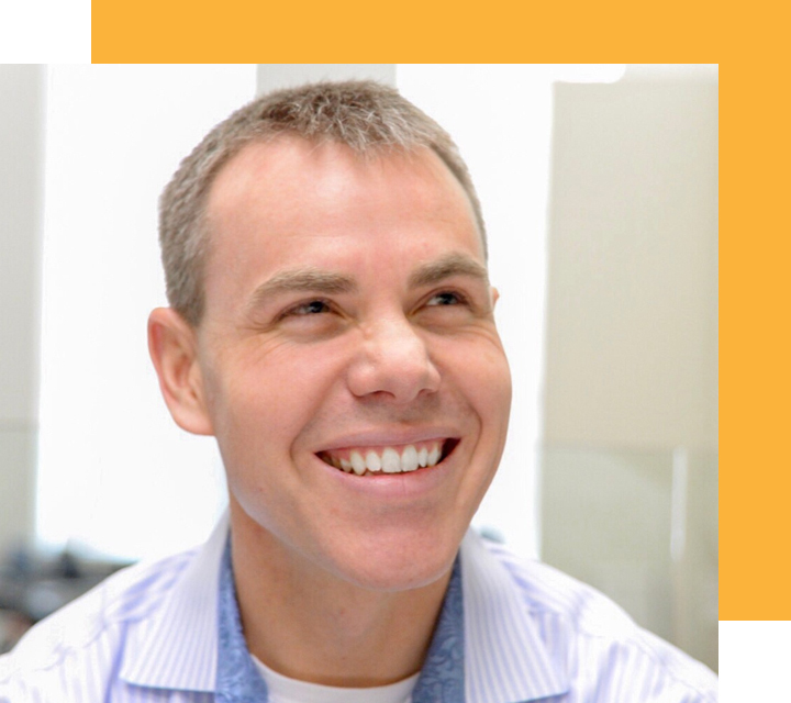 Headshot of Jay Coppoletta, Chief Corporate Development and Legal Officer of PEAK6 Investments. Jay is a young White person who presents as male. He is looking up from below the camera and smiling at something off camera. His light brown hair is trimmed short.