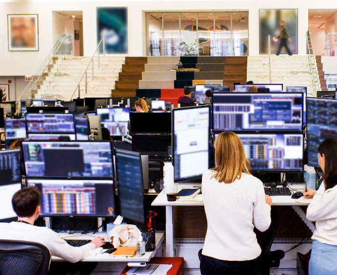 Image of traders working in the trading office, each desk set up with multiple screens to monitor the markets.