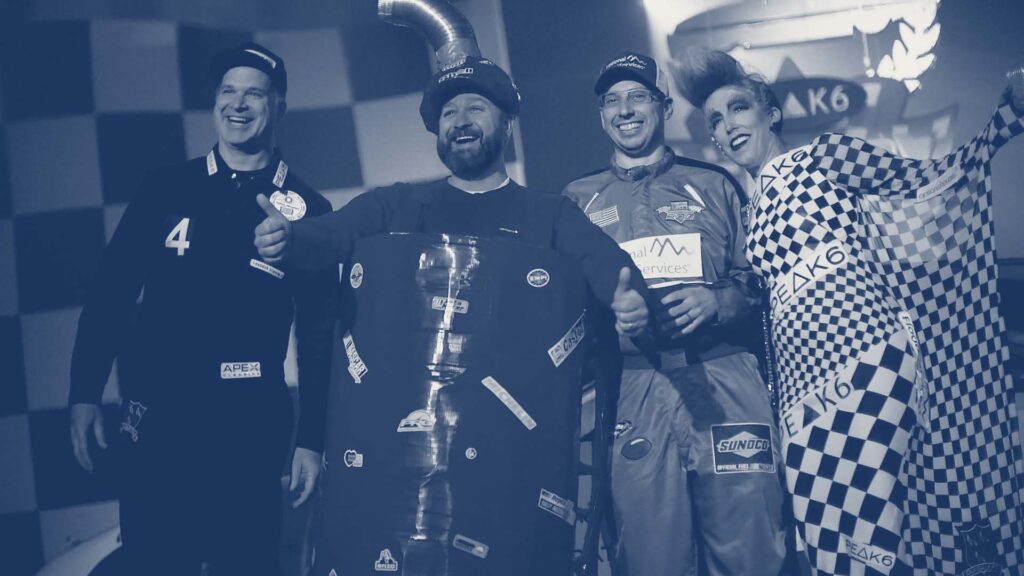 Image of four happy people dressed in costume for a race car themed party.