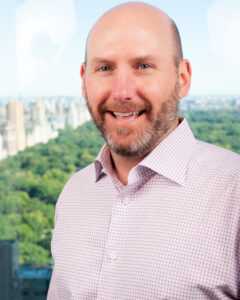 Headshot of Tom Simpson, CEO of PEAK6 Capital Management. Tom is late middle-aged White person and presents as male. His hair is closely shaved; he looking over his shoulder and appears to be smiling at a person who is off camera.