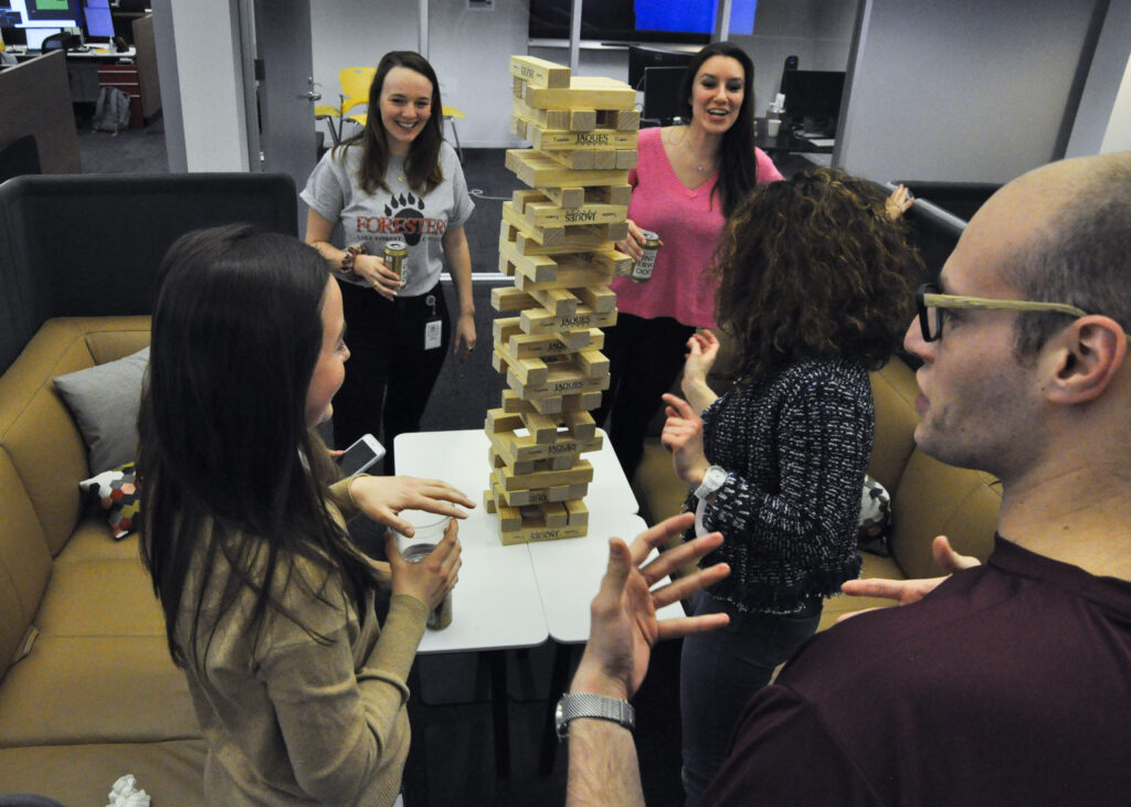 A group of PEAK6 employees play a balancing block game while socializing.